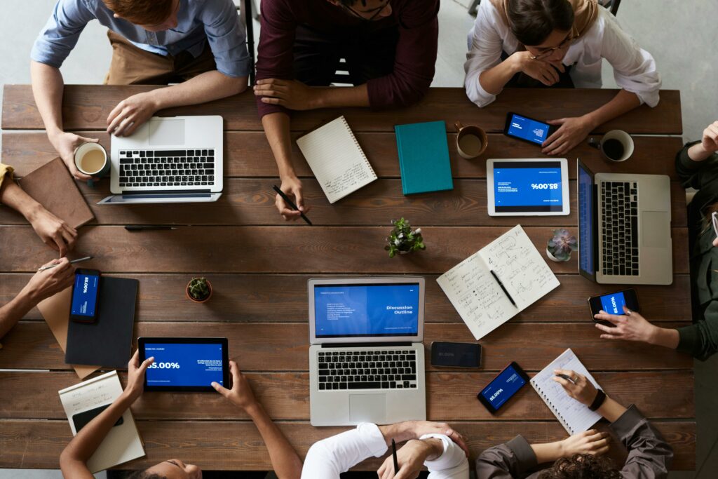 forum de discussion personnes autour d'une table avec des ordinateurs et tablettes